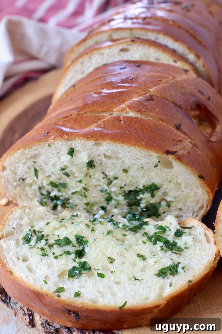 Sliced homemade garlic bread on a wooden cutting board, ready to be served.