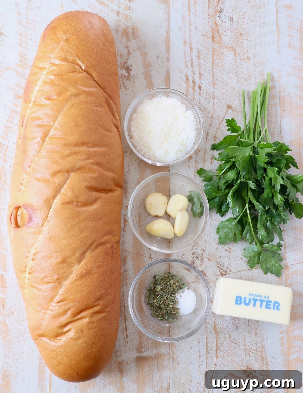 Ingredients for homemade garlic bread laid out on a wooden surface.