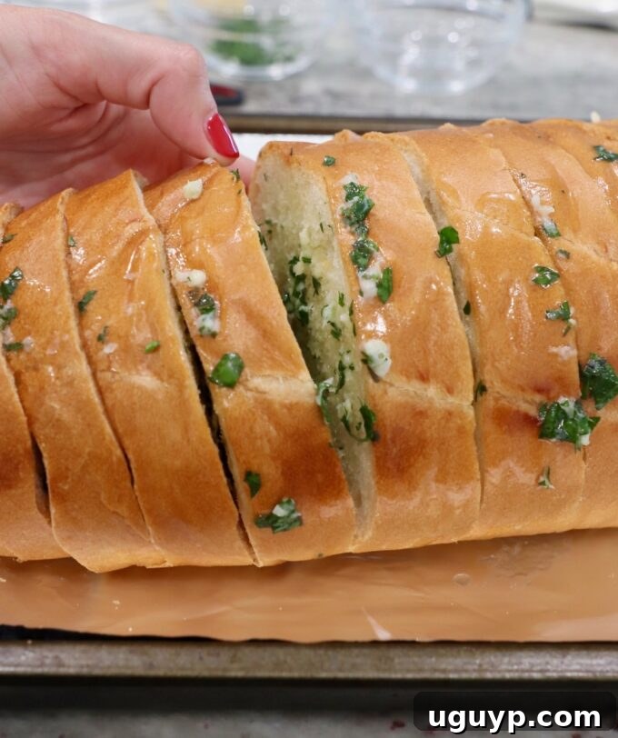 Sliced bread with garlic herb butter generously spread between each segment.