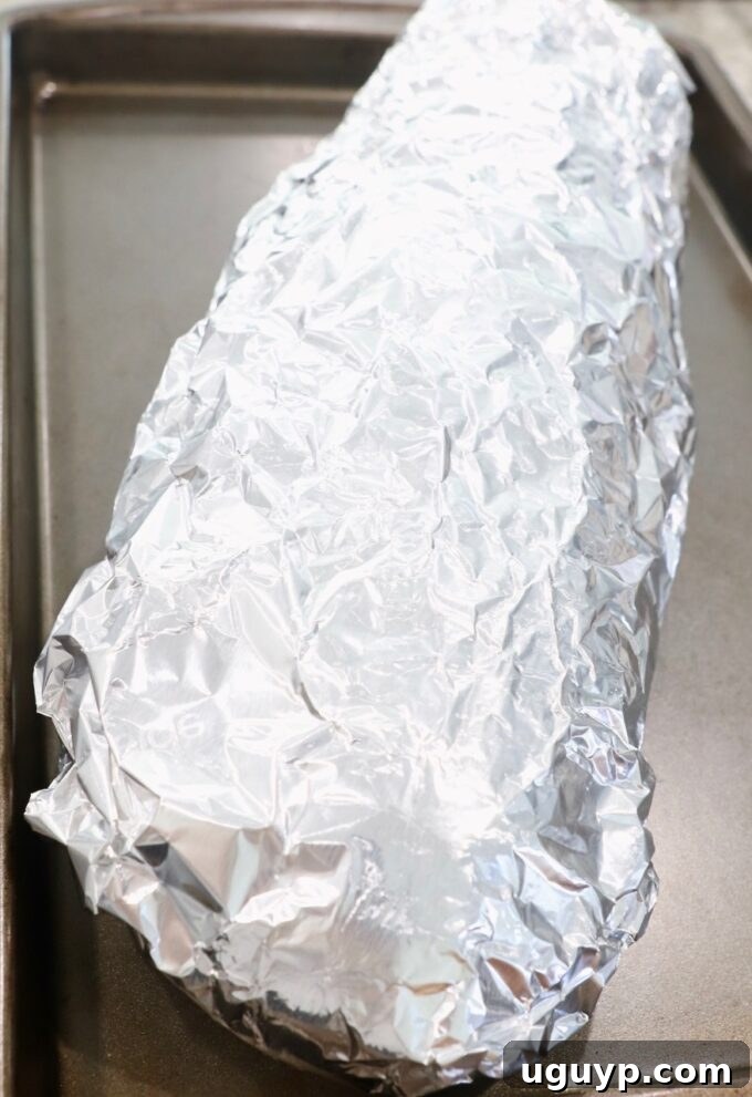 Garlic bread wrapped in foil on a baking sheet, ready for baking.