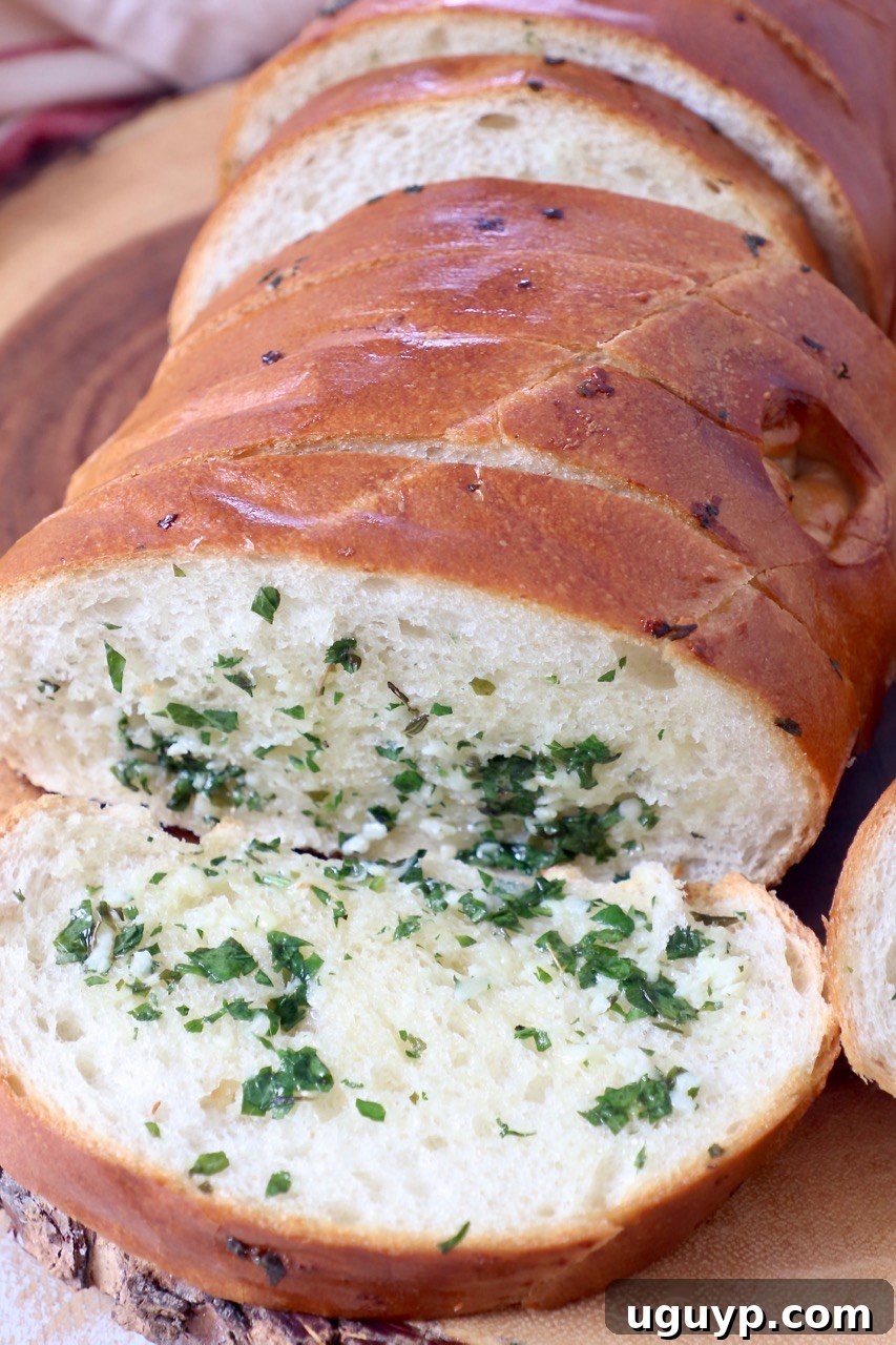 A whole loaf of sliced garlic bread on a wooden cutting board, ready for serving.
