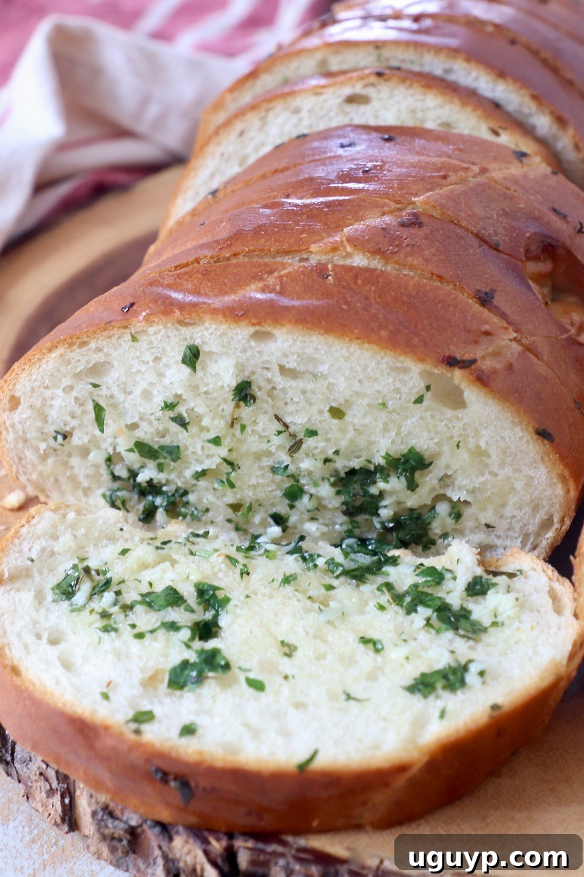 A close-up of beautifully sliced garlic bread on a wooden cutting board, showcasing its golden crust and flavorful interior.