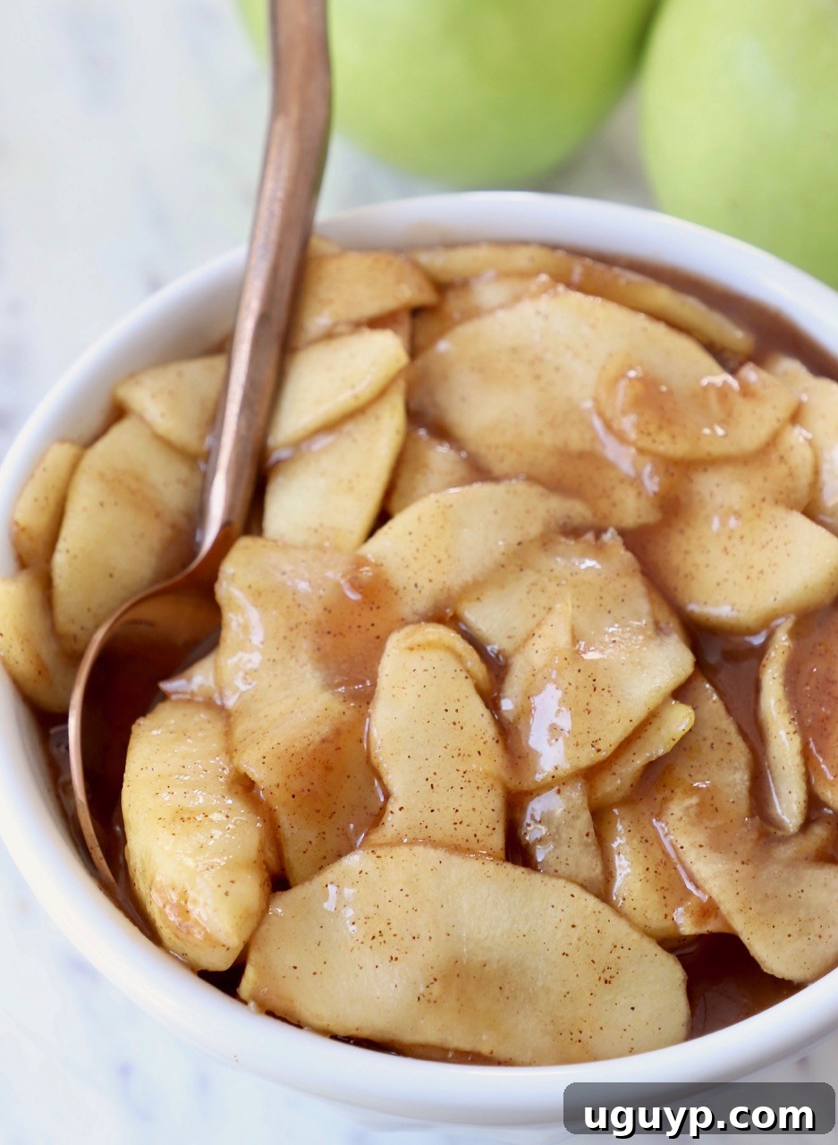 A bowl of fresh homemade apple pie filling with a copper spoon, ready to be enjoyed.