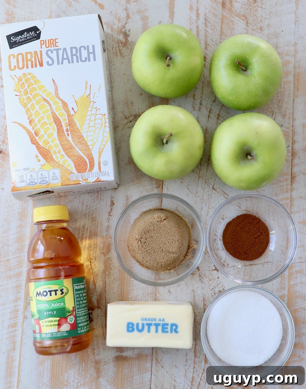 Fresh ingredients laid out on a table, including apples, butter, sugars, and spices, ready for making apple pie filling.