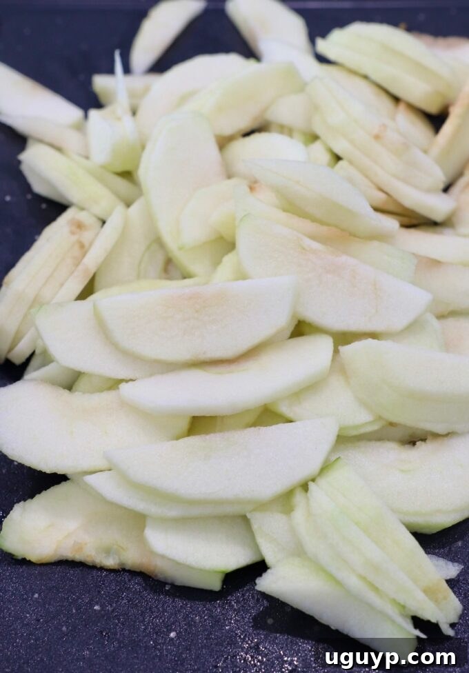 Thinly sliced apples arranged on a wooden cutting board, ready for cooking.