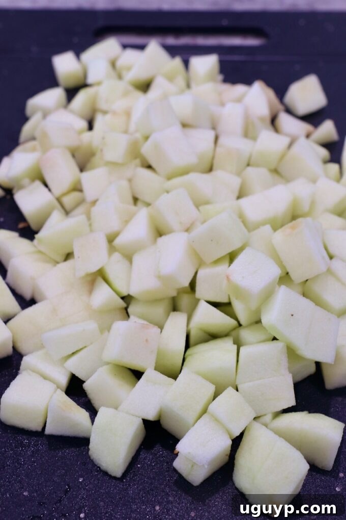 Diced apples on a cutting board, prepared for a chunky apple pie filling.