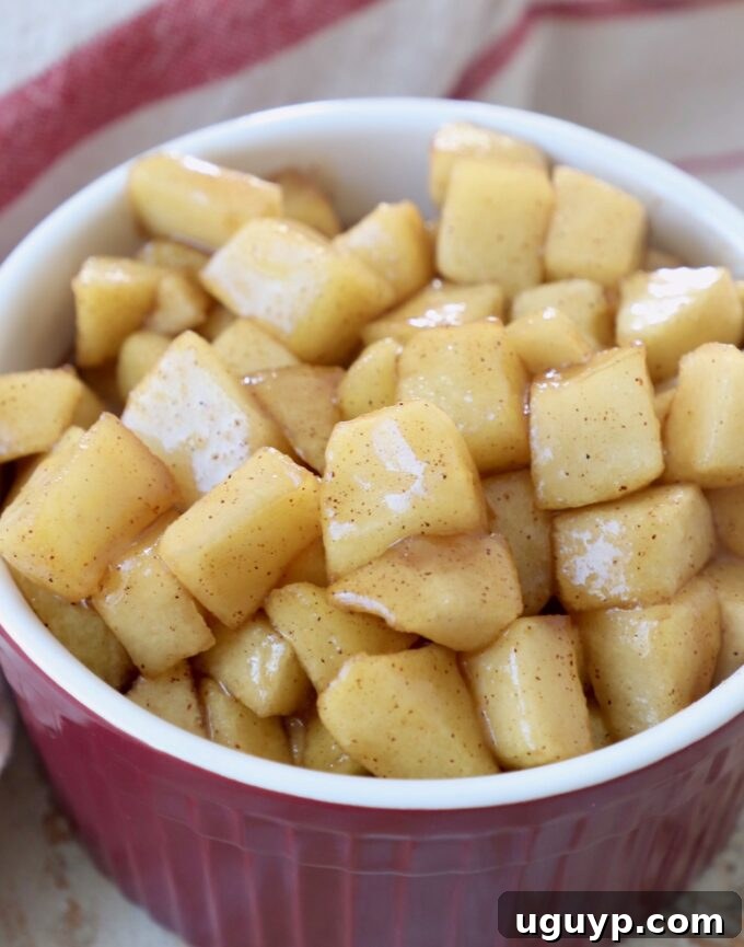 A bowl of cooked diced apple pie filling, showcasing a chunkier texture.