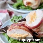 A bacon wrapped stuffed chicken breast cut in half, revealing the creamy blue cheese and cream cheese filling, served on a plate.