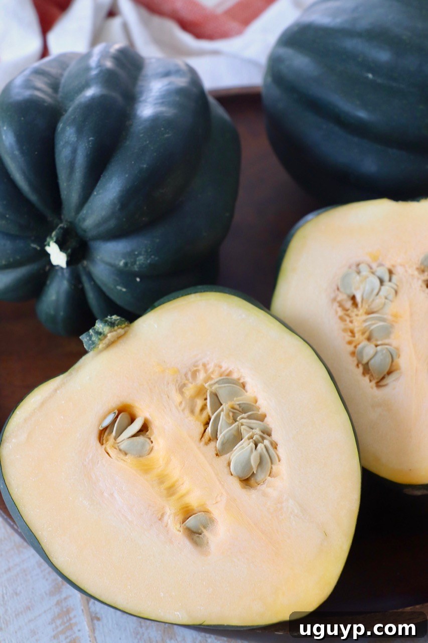 raw acorn squash whole and cut in half on wood serving tray, ready for cooking