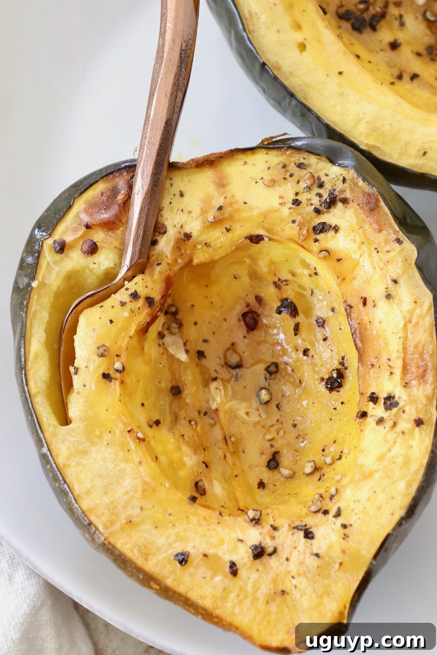 roasted acorn squash cut in half on plate with fork, ready to be eaten