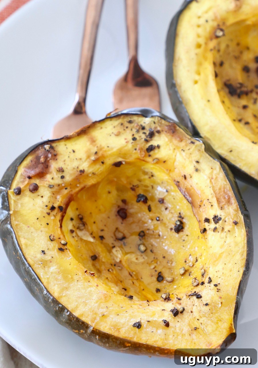 roasted acorn squash cut in half on plate with two forks, ready to be shared and enjoyed