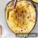 roasted half of acorn squash on plate with fork, perfectly cooked