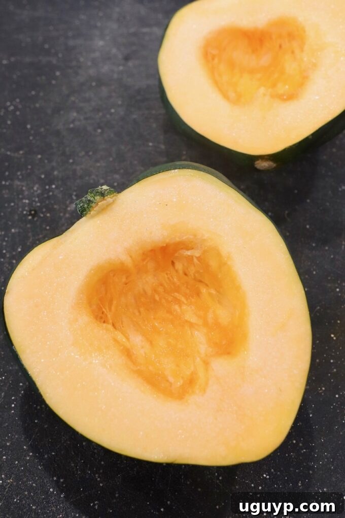 acorn squash cut in half on cutting board with the seeds removed, ready for cooking