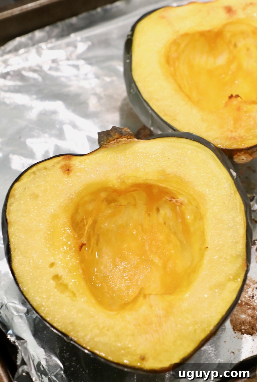 roasted acorn squash cut in half, glistening on a foil-lined baking sheet, fresh from the oven