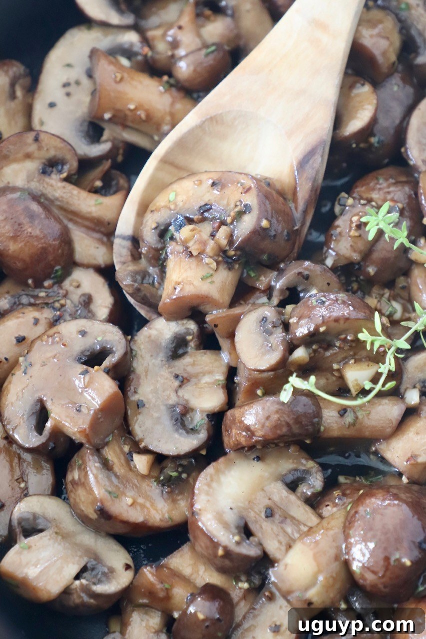 Sauteed mushrooms in a skillet with a wooden spoon, ready to be served