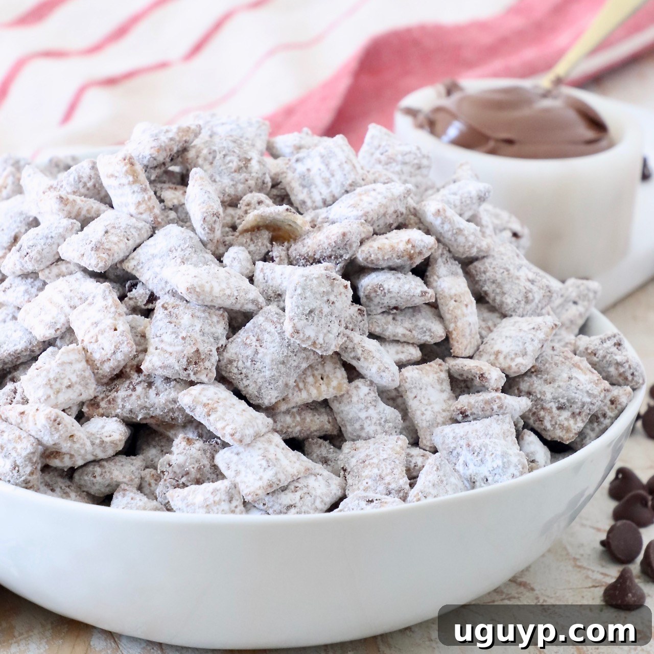 A white bowl filled to the brim with perfectly coated Nutella Muddy Buddies.