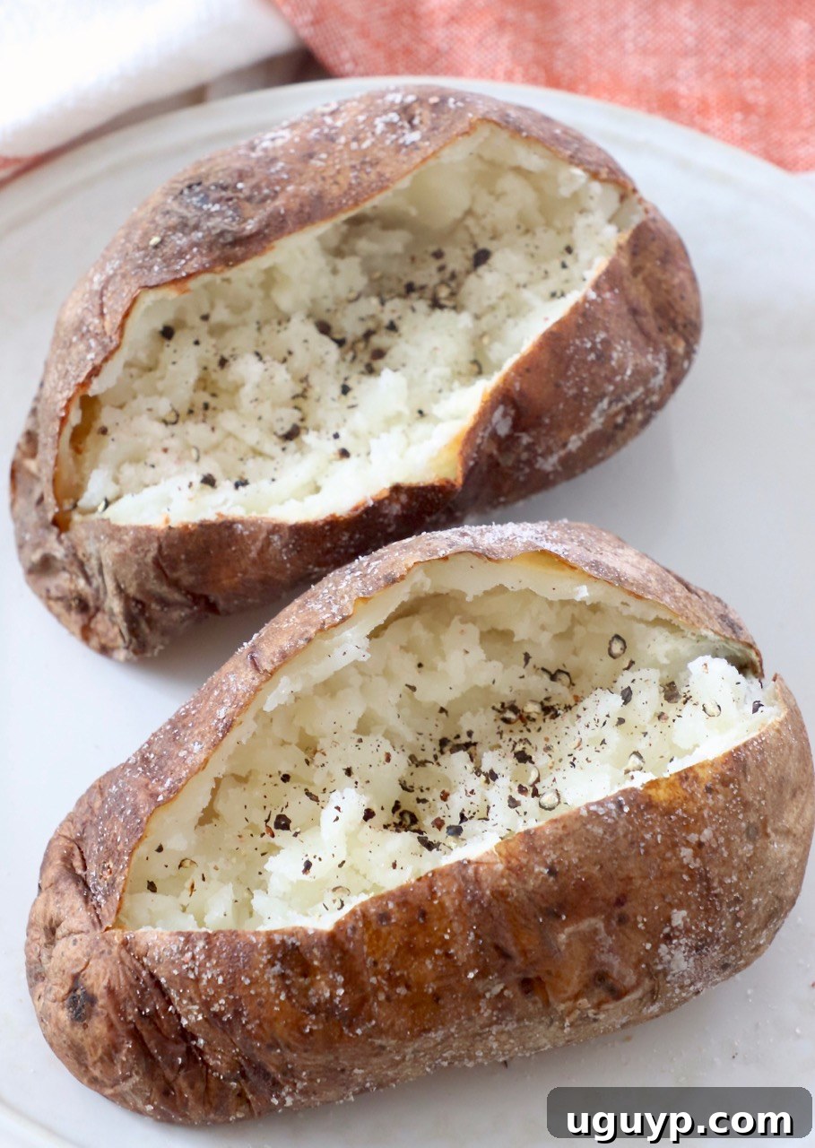 sliced open baked potatoes on plate with black pepper sprinkled inside