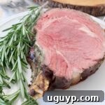slice of bone-in prime rib on white plate with fresh rosemary sprigs