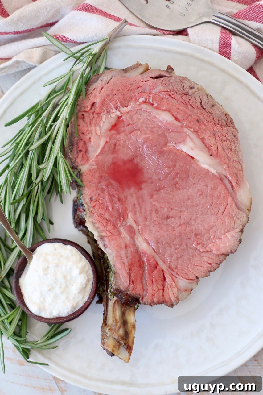 slice of cooked prime rib on plate with horseradish sauce in bowl