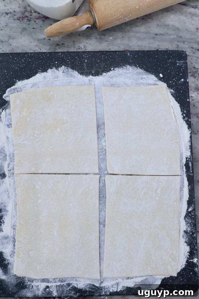 sheet of puff pastry dough cut into 4 squares on cutting board