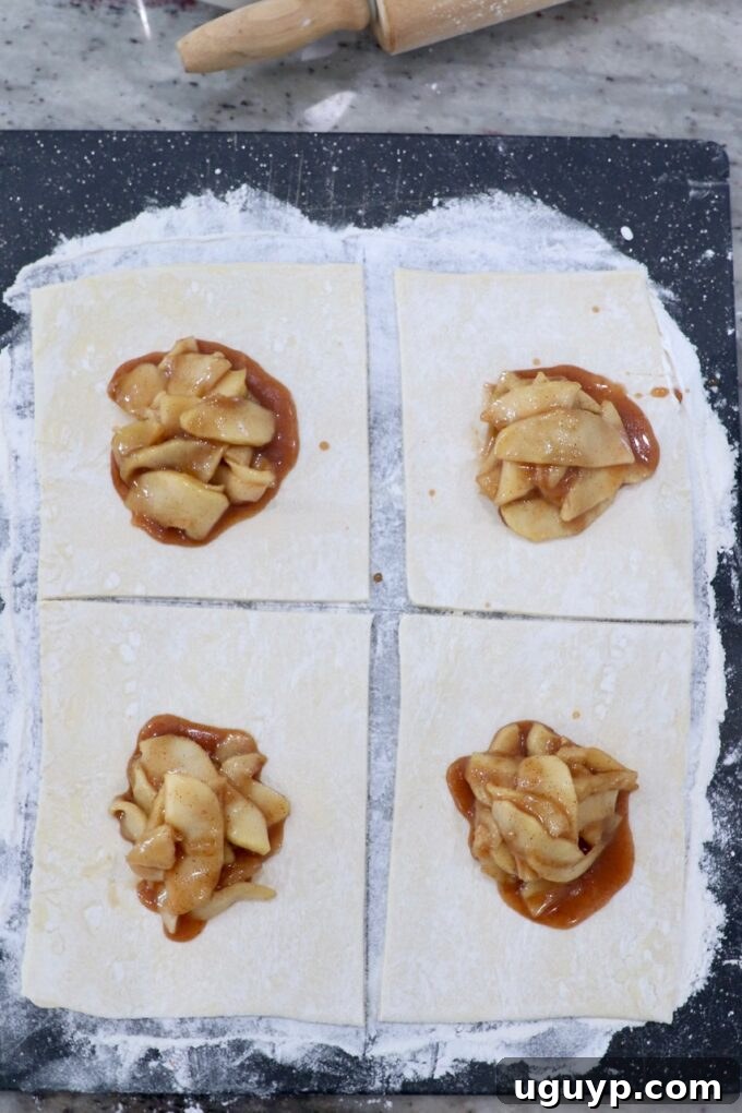 puff pastry sheet of dough on cutting board, topped with apple pie filling