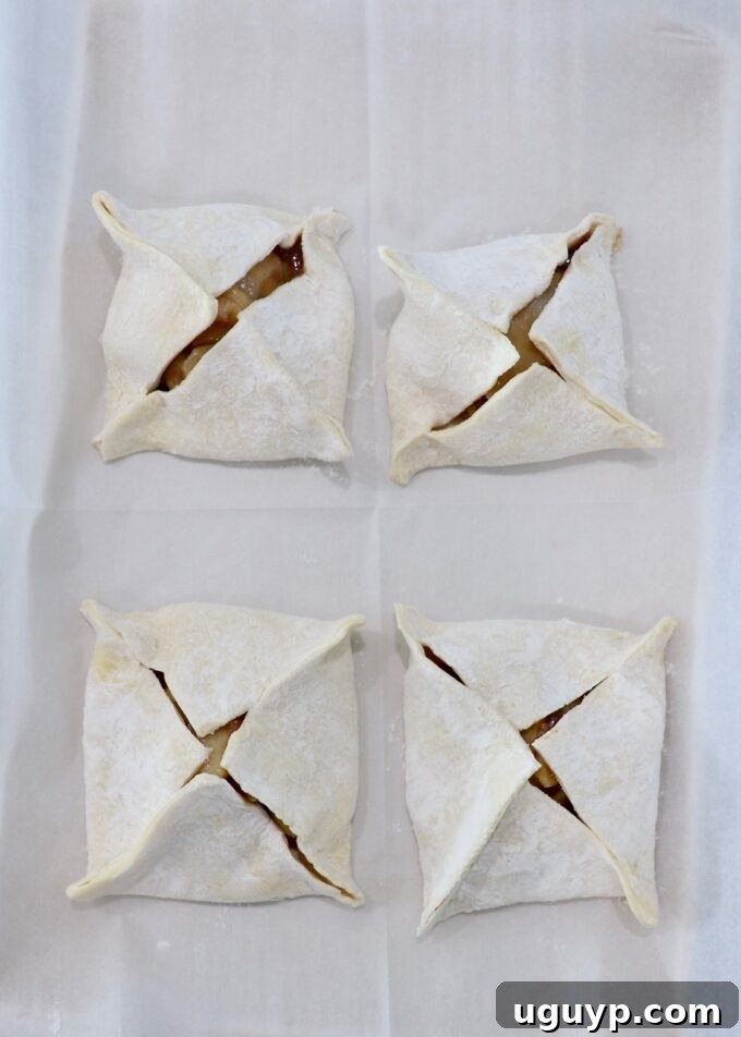 four uncooked apple danish on parchment paper