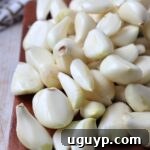 Peeled cloves of garlic on a brown cutting board
