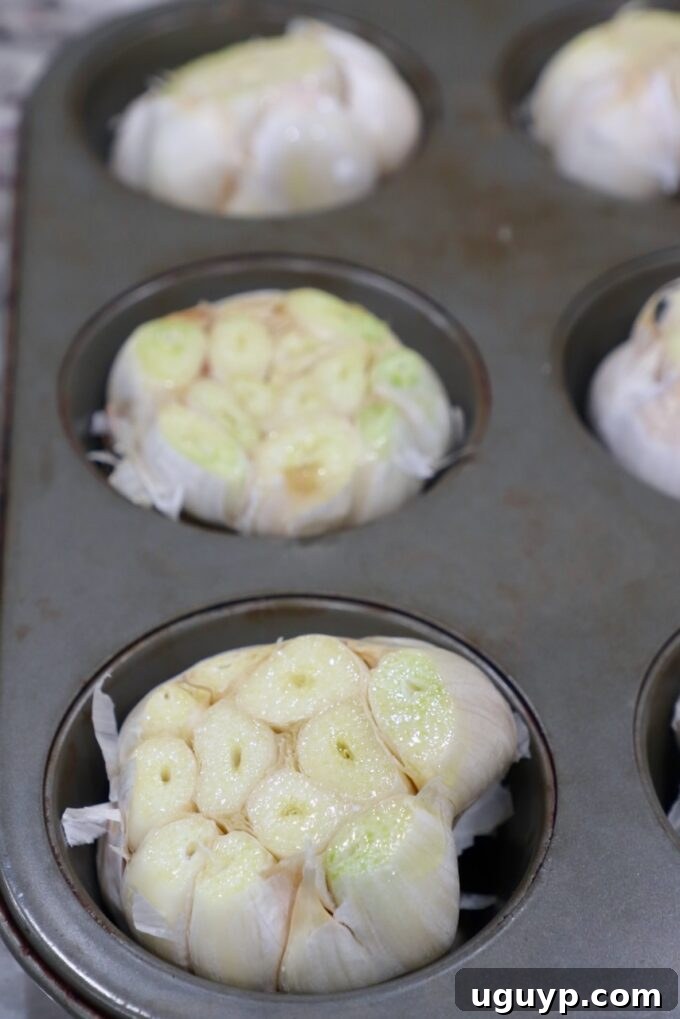 Multiple heads of garlic in a muffin tin, ready for batch roasting.