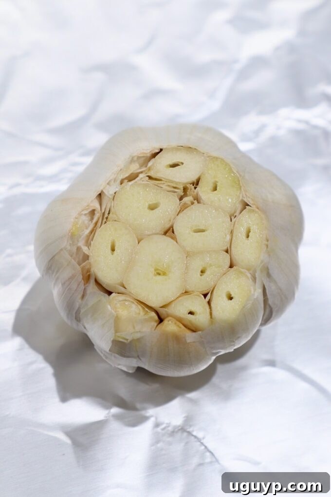 Sliced garlic head placed on a piece of aluminum foil, ready for oil.