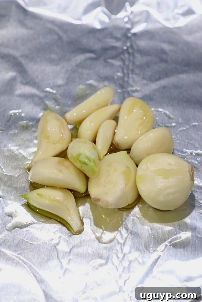 Peeled garlic cloves tossed with olive oil on a piece of foil.