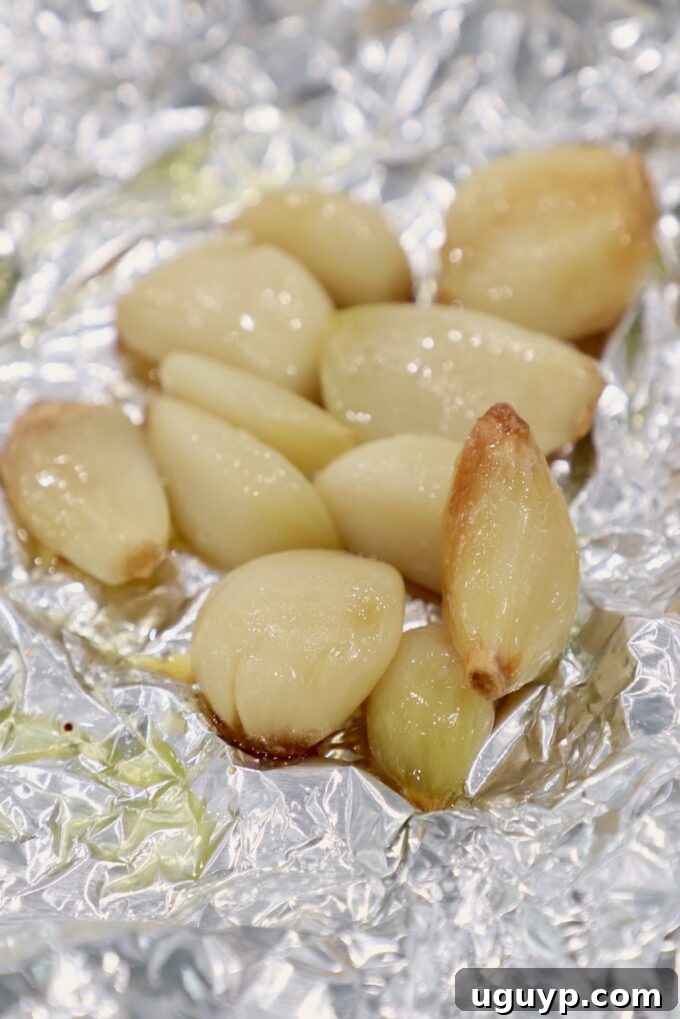Perfectly roasted garlic cloves, golden brown and tender, on foil.