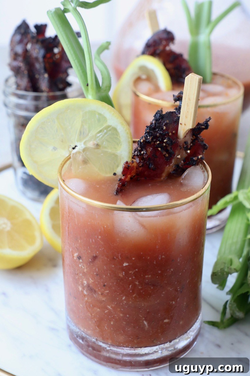 A perfectly garnished Bloody Mary cocktail with candied bacon and a lime wedge