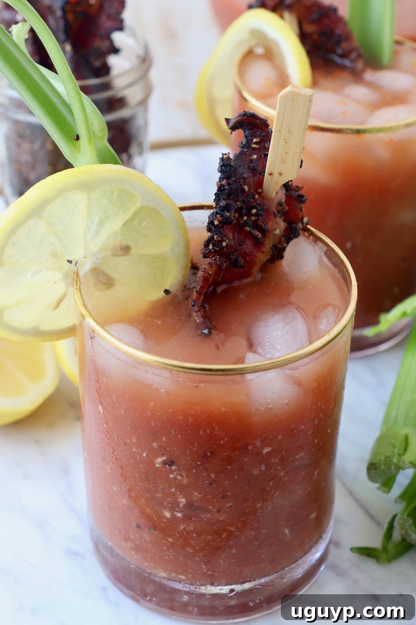 A Bloody Mary cocktail garnished with crispy bacon and a lemon slice