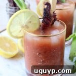 bloody mary in glass with lemon wedge and candied bacon