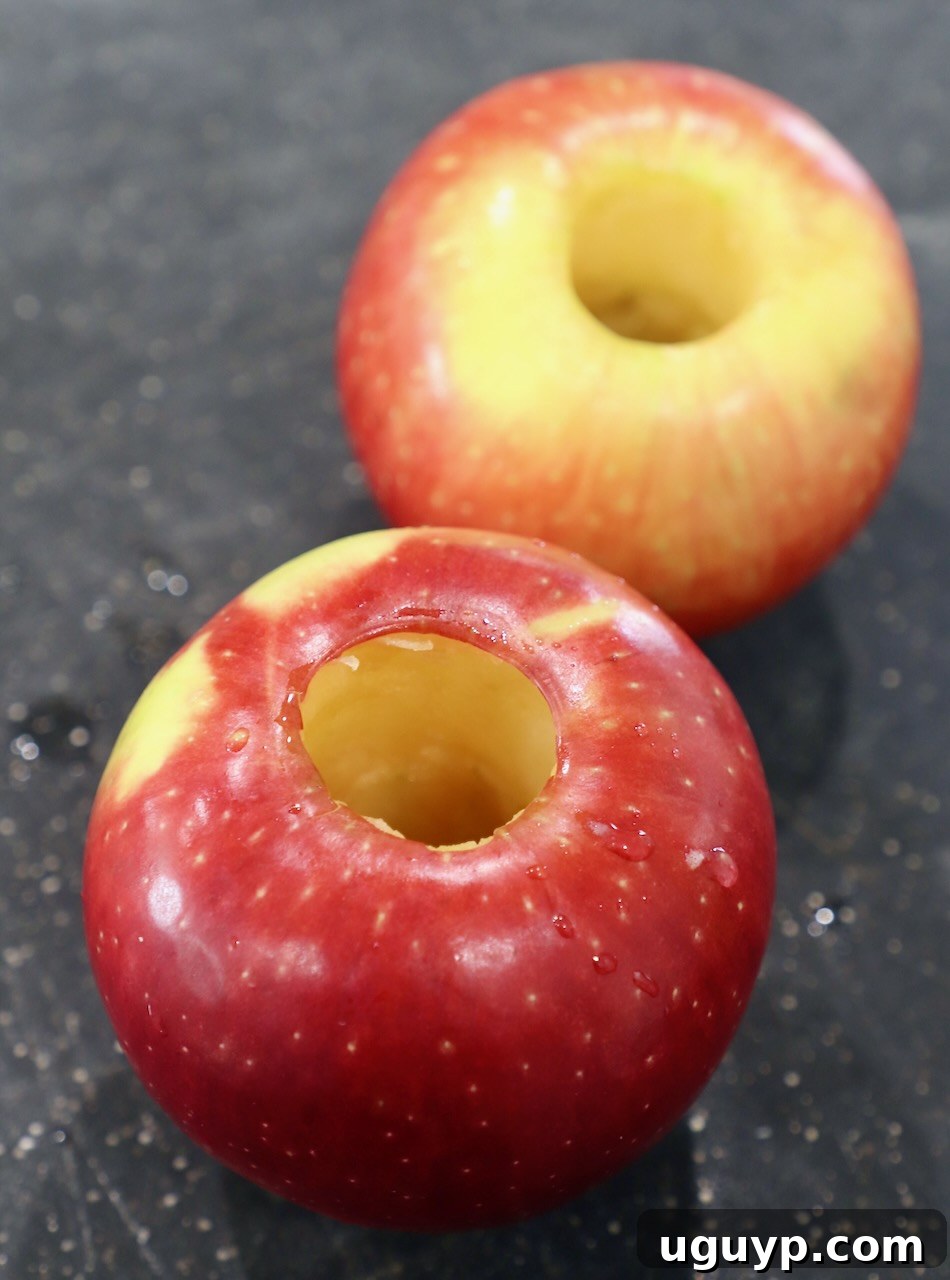 Two cored apples ready for slicing on a wooden cutting board