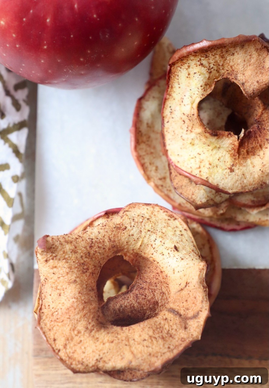Stack of crispy homemade apple chips on a wooden board
