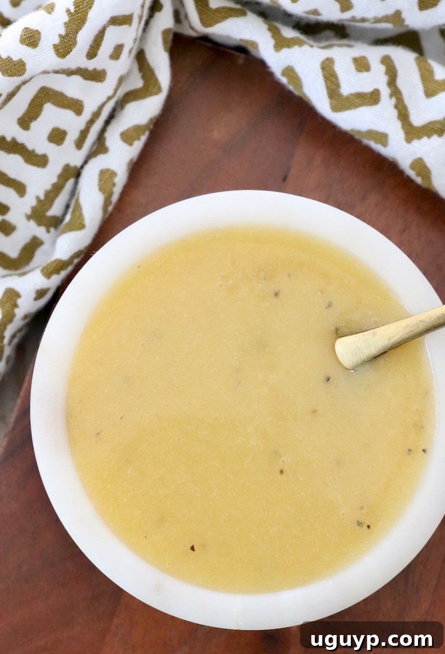 A small bowl of creamy honey mustard dressing with a spoon, ready to be served.