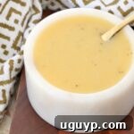 A small bowl of creamy honey mustard dressing with a spoon, ready to be served.