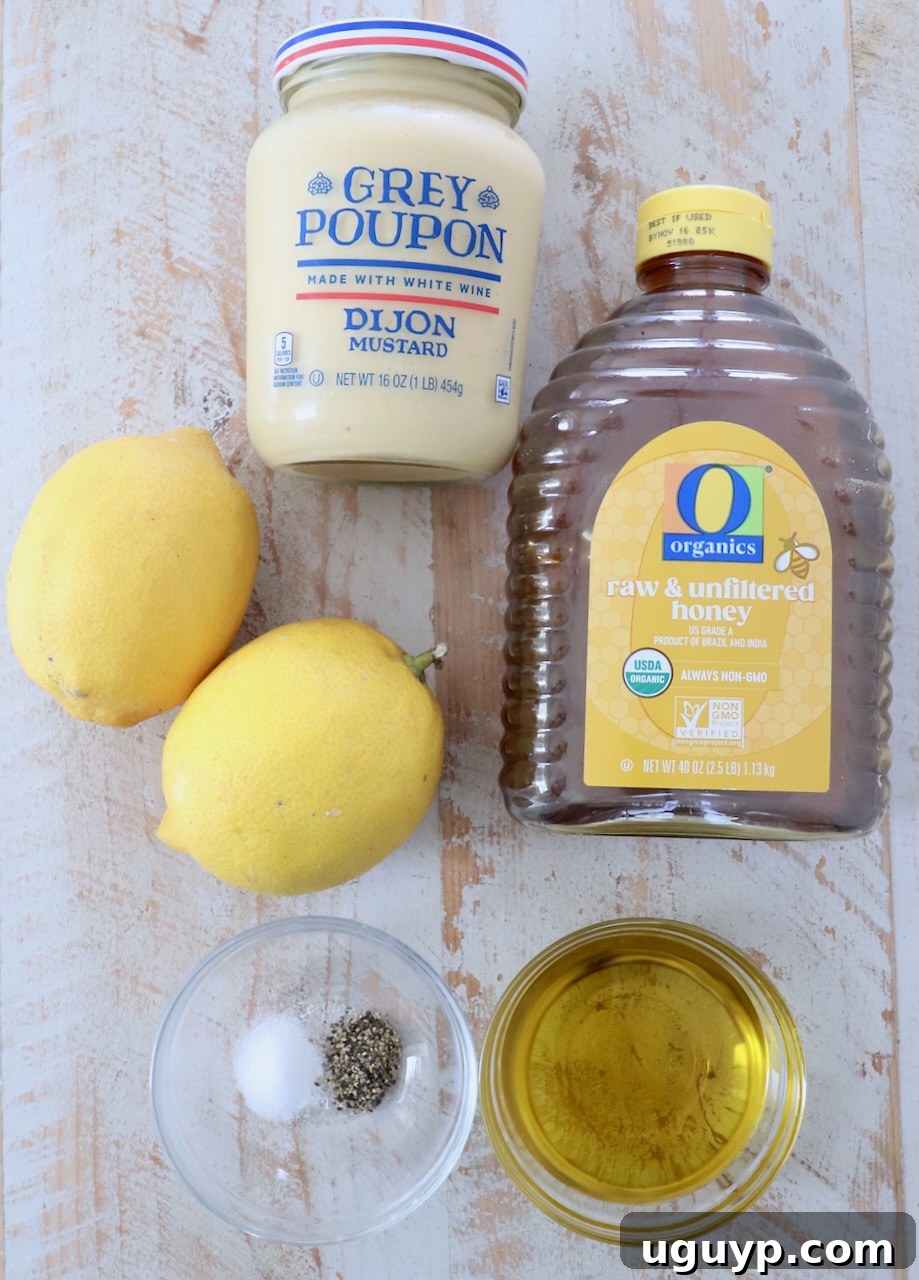A collection of fresh ingredients laid out on a white wooden board for making honey mustard dressing.