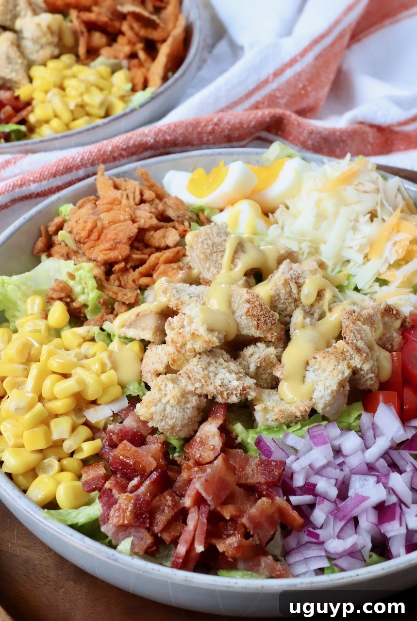 A vibrant crispy chicken salad in a large bowl, drizzled generously with honey mustard dressing.