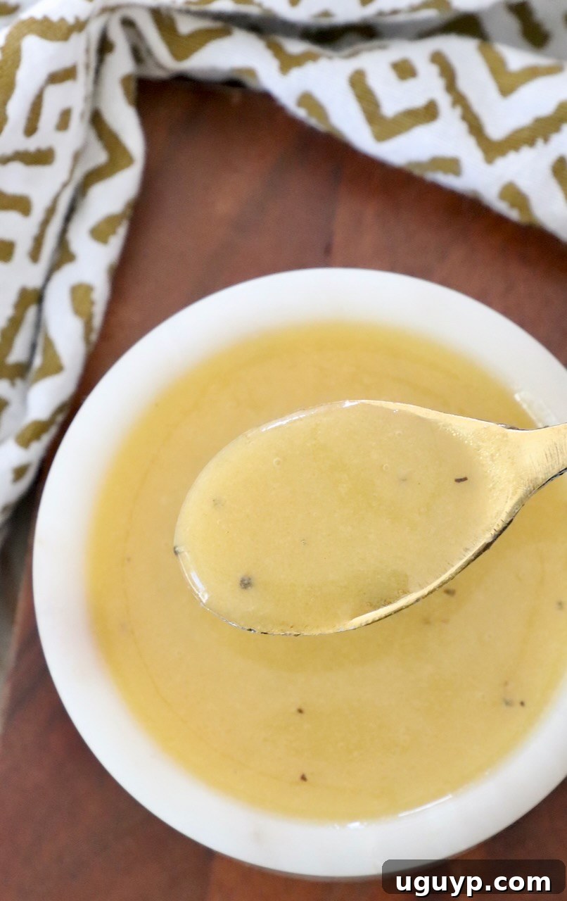 A close-up of creamy honey mustard dressing in a small bowl with a mini spoon.