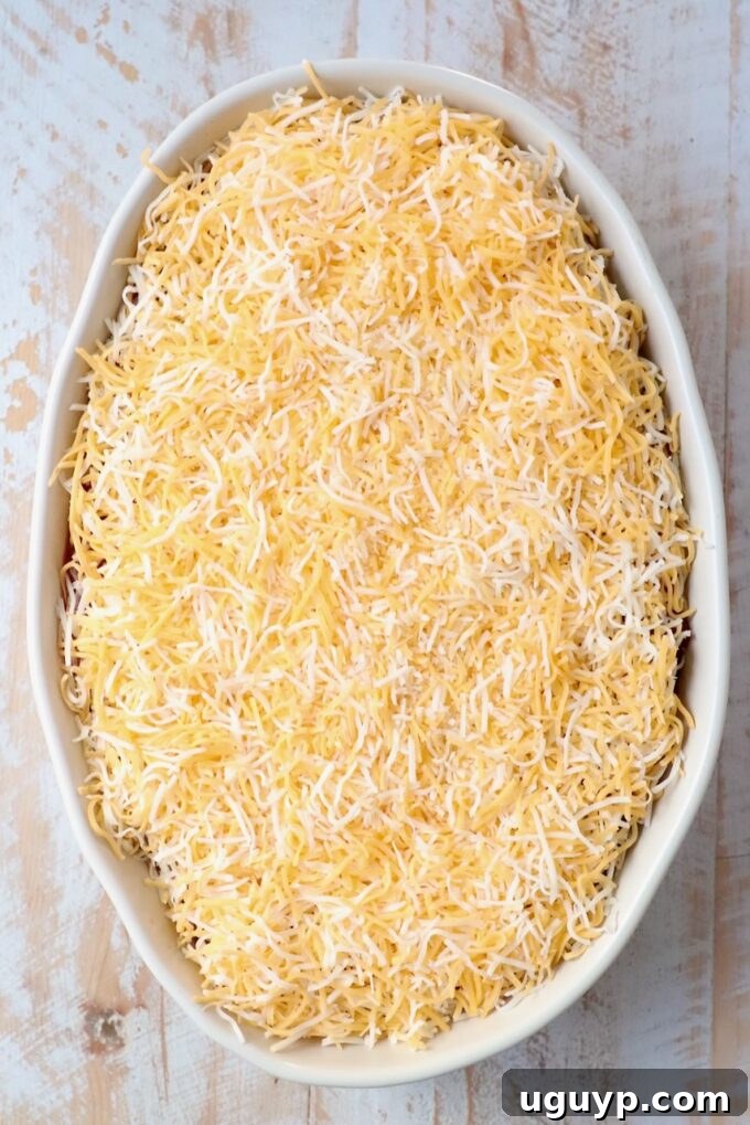 Shredded Mexican cheese generously sprinkled over salsa in a casserole dish