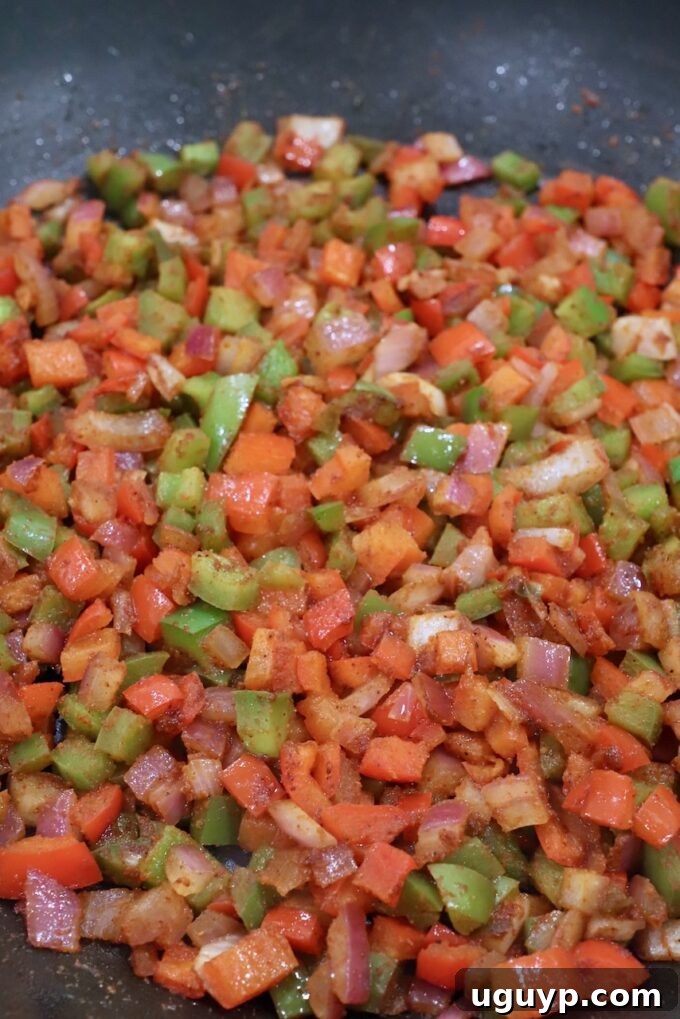 Fajita seasoned diced peppers and onions cooking in a skillet