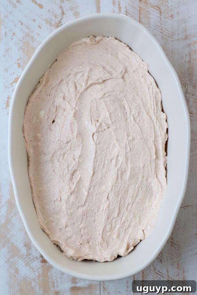 Creamy fajita seasoned cream cheese mixture spread over refried beans in a casserole dish