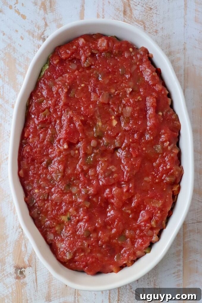 Chunky salsa carefully spooned over guacamole in a casserole dish