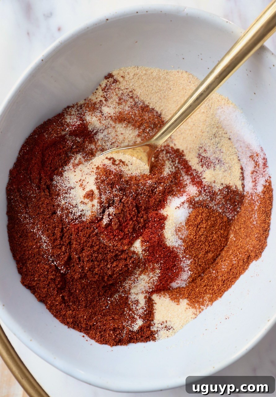 A bowl of rich golden-brown chicken wing seasoning with a gold spoon, ready to be used on various chicken dishes.