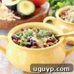 Crockpot Taco Soup in yellow crock with gold spoon, topped with cheddar cheese and fresh cilantro