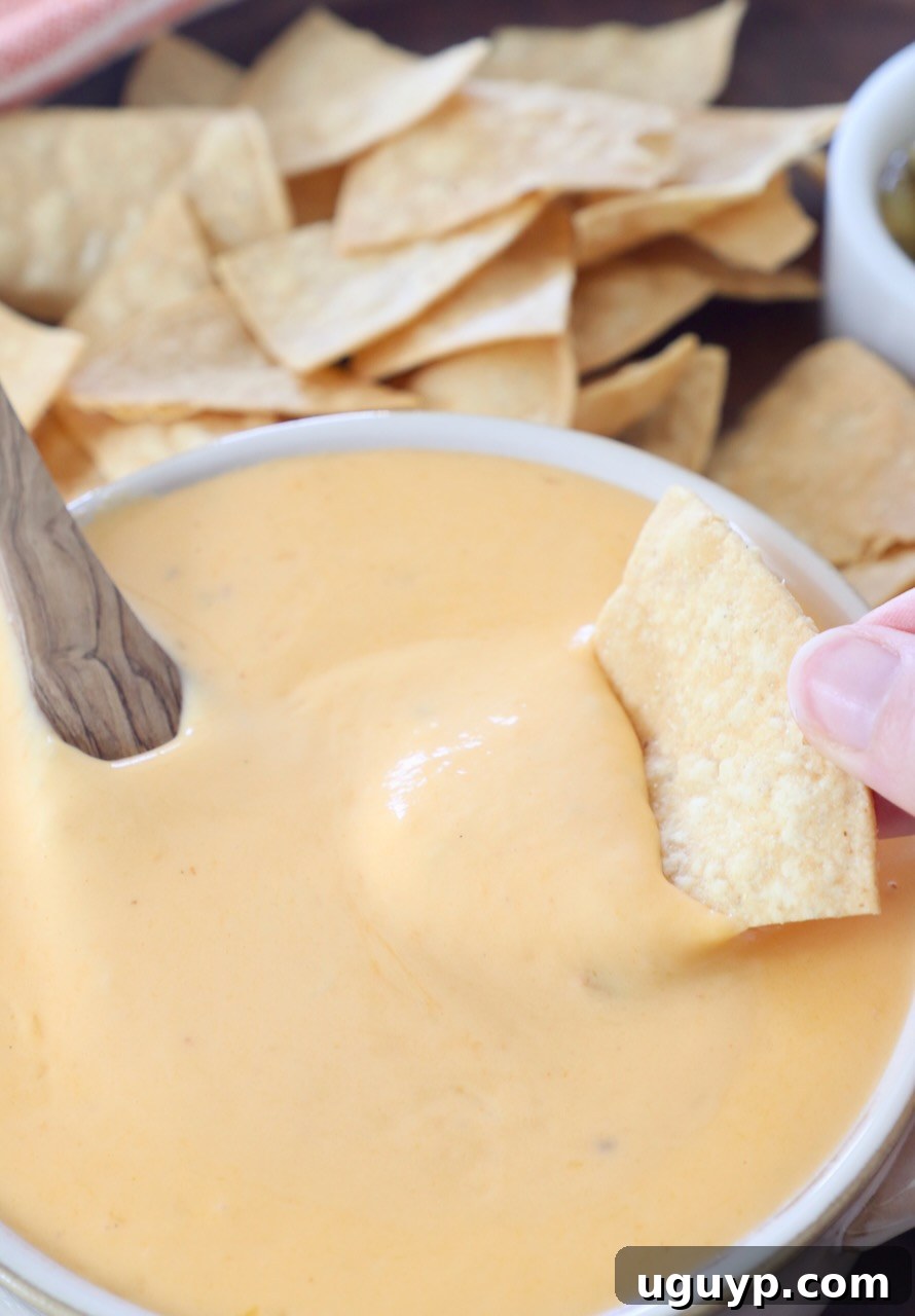 tortilla chip dipped into bowl of nacho cheese sauce
