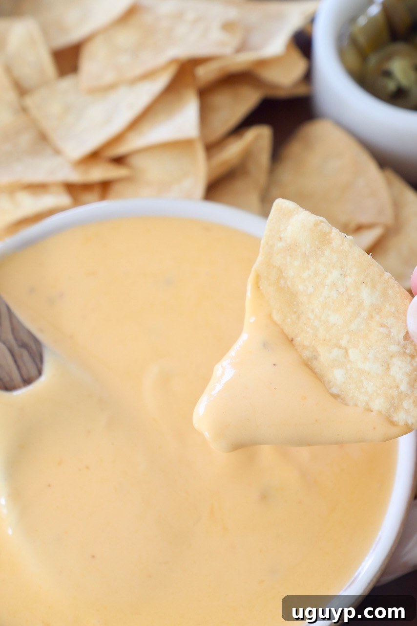 tortilla chip dipping up nacho cheese sauce