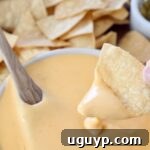 tortilla chip dipped into bowl of nacho cheese sauce